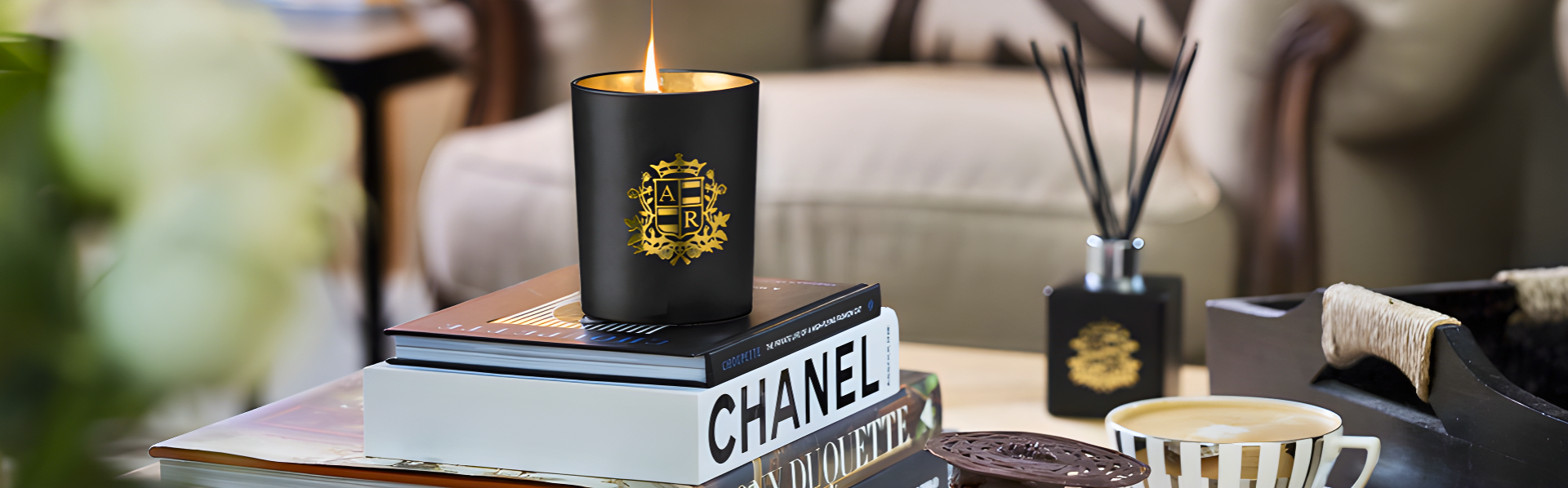Chanel candle on books with a blurred background of a living room.