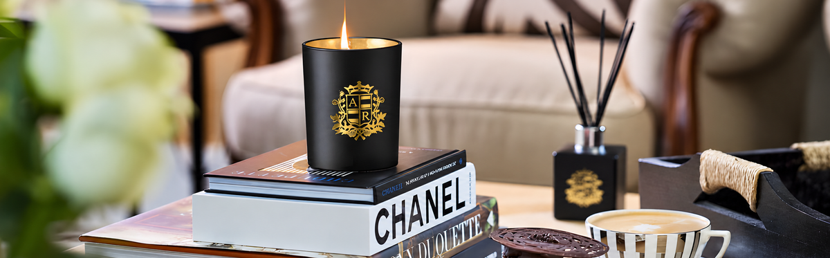 Chanel candle on books with a blurred background of a living room.