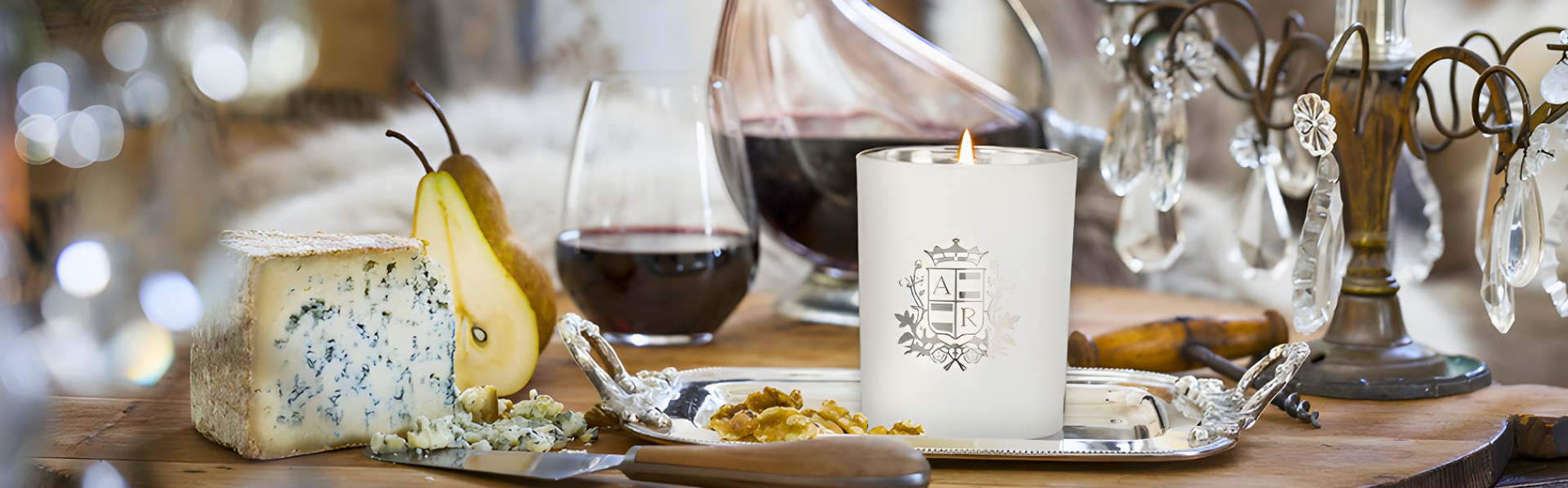 Table setting with cheese, pear, wine, and a candle with decorative elements.