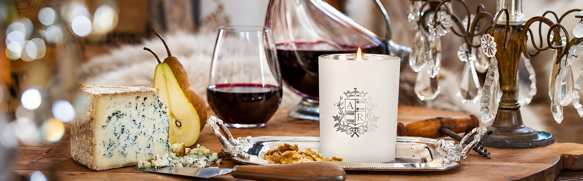 Table setting with cheese, pear, wine, and a candle with decorative elements.